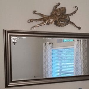 A mirror with an octopus on it above the window.