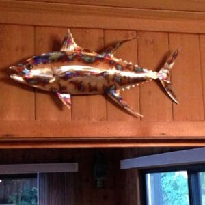 A metal fish hanging on the wall of a room.