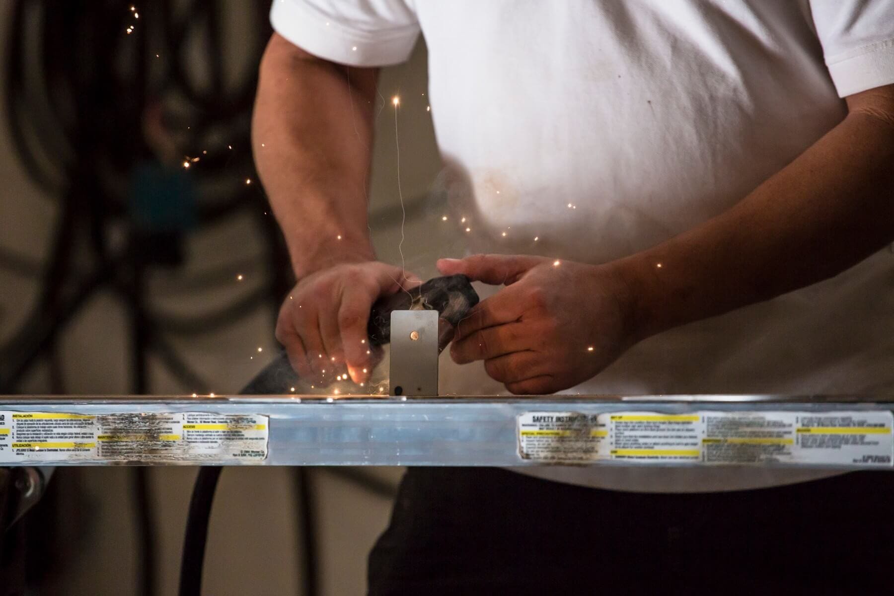 A person using an angle grinder on metal.